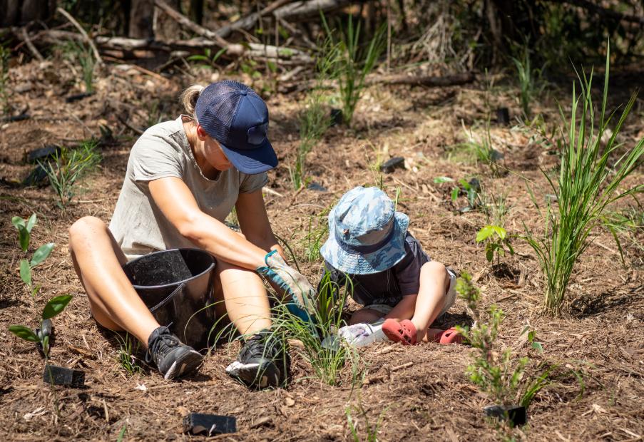 Mother and son planting native grasses in Queensland